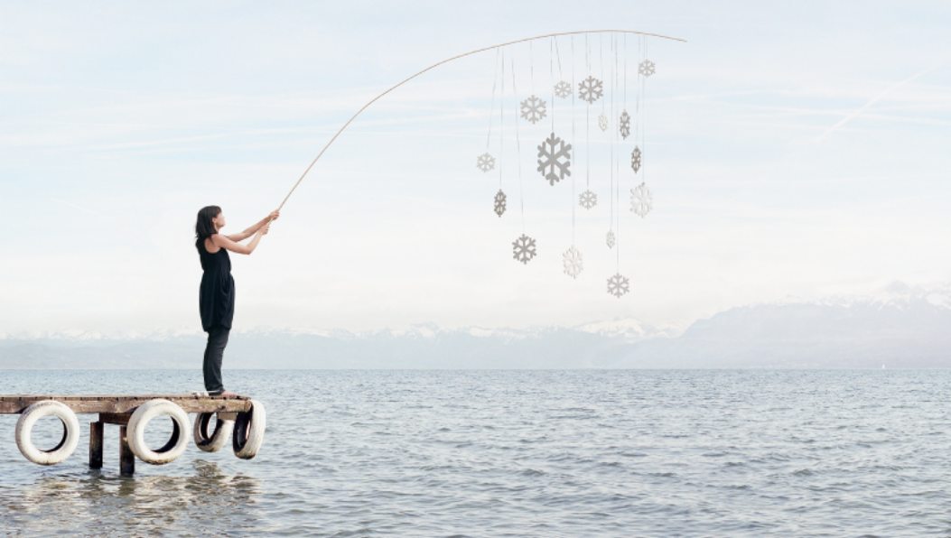 A psychotherapist calmly stands on the end of a pier dangling snow flakes from  a fishing rod